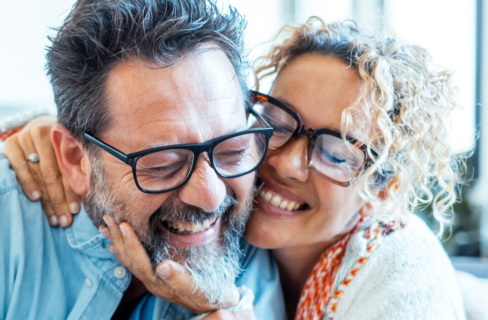 A smiling middle-aged couple wearing glasses and hugging showcasing clear and healthy vision.